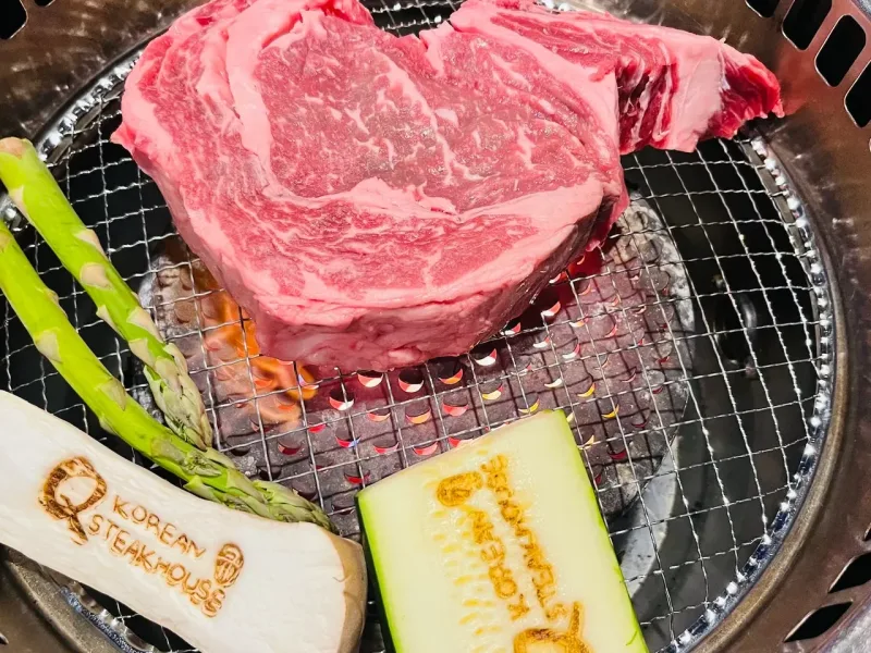 Ribeye steak on Korean BBQ grill with Q Korean Steakhouse branding