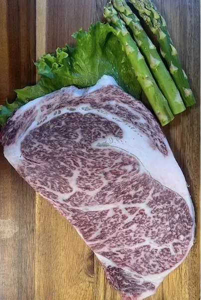 Premium wagyu ribeye with asparagus on wooden board