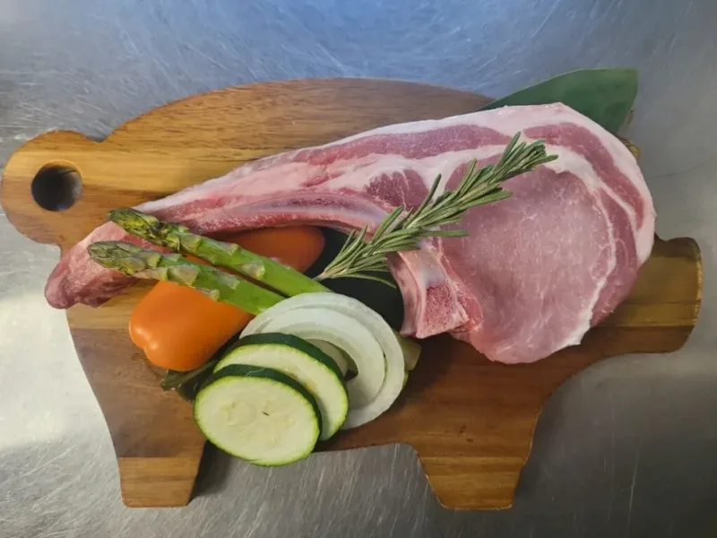 Tomahawk pork chop with vegetables on wooden board